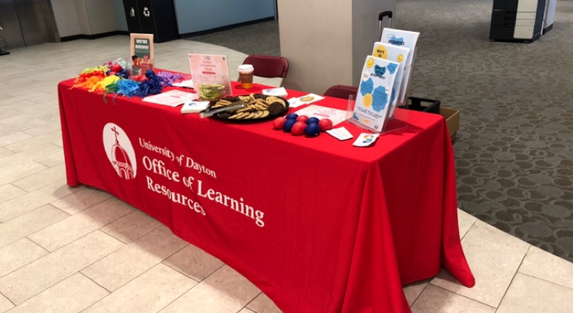 Table with red tablecloth, flyers and stress balls on it promoting autism acceptance week.