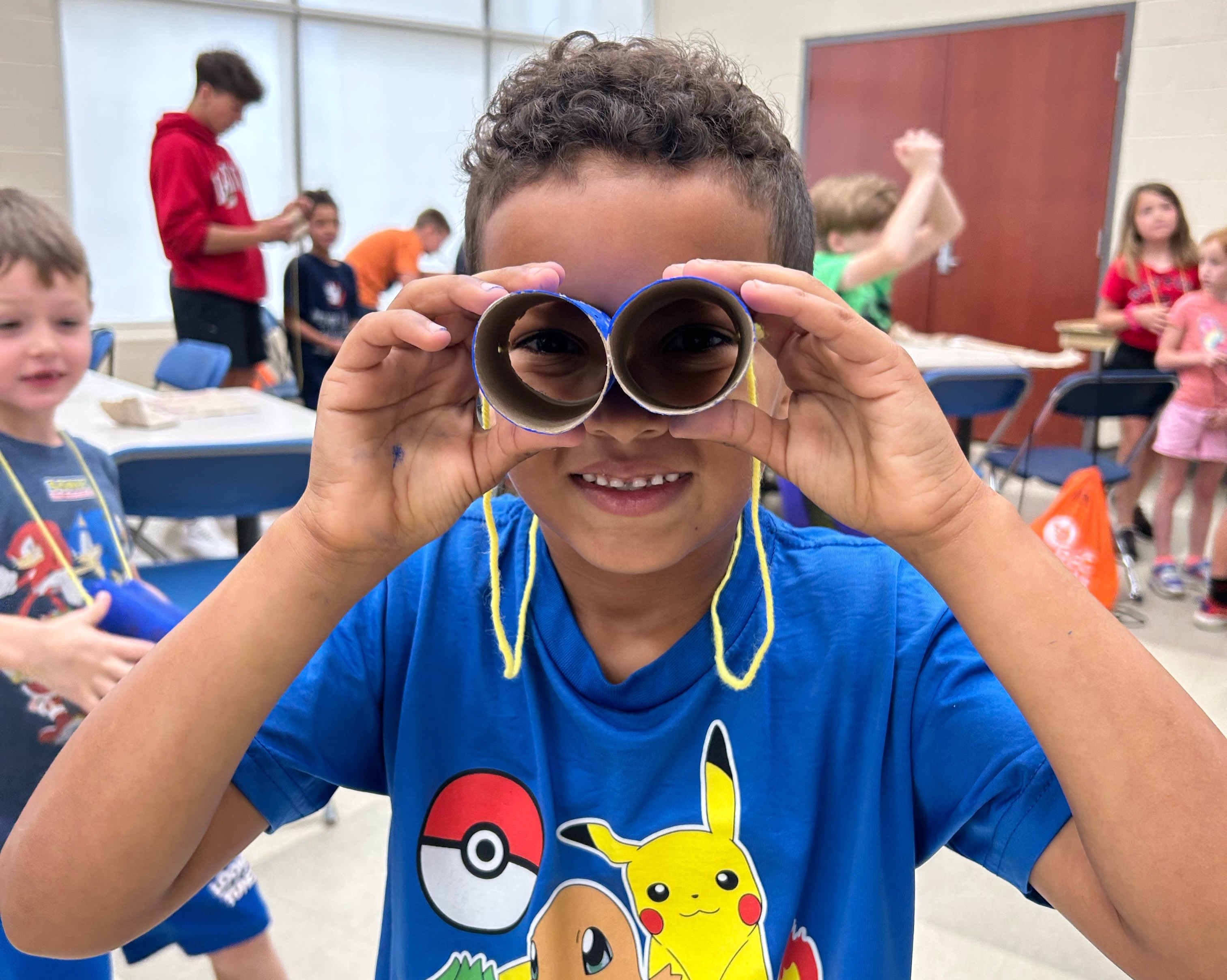 A RECkids camper looking through binoculars made by themselves in an arts and craft activity.